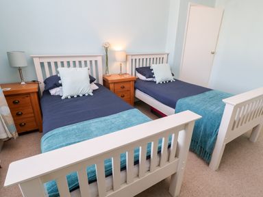 A bedroom with two single beds with blue bedding and wooden nightstands at Lightkeeper House in Amble-by-the-Sea