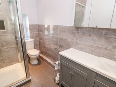 A bathroom with a shower enclosure a toilet and a gray vanity unit at Lightkeeper House Amble-by-the-Sea