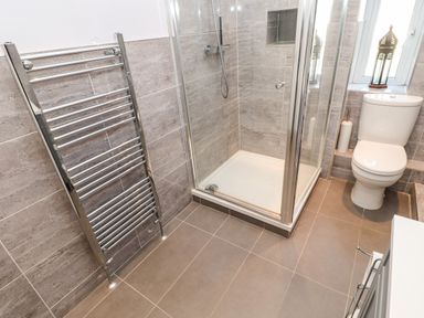 A bathroom with a shower enclosure a toilet and a chrome towel radiator at Lightkeeper House in Amble-by-the-Sea