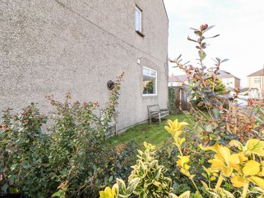 An outdoor area with bushes and a bench next to a house at Lightkeeper House in Amble-by-the-Sea