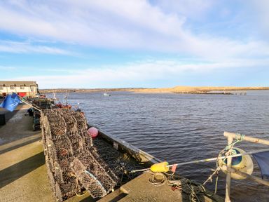A harbor with fishing traps on the pier and boats in the water at Lightkeeper House in Amble-by-the-Sea