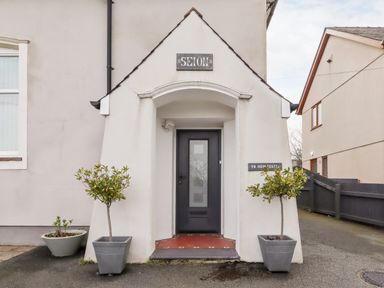 Front entrance of a house with a black door and two potted plants at Yr Hen Festri in Y Felinheli