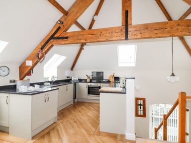 A kitchen with wooden beams white cabinets black countertops and wooden floor at Yr Hen Festri in Y Felinheli