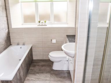 A bathroom with a bathtub toilet sink and small plants on the window at Yr Hen Festri in Y Felinheli