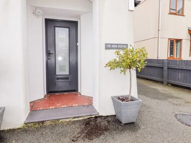 An entrance door with glass panels and a plant in a pot outside next to a sign reading Yr Hen Festri at Y Felinheli