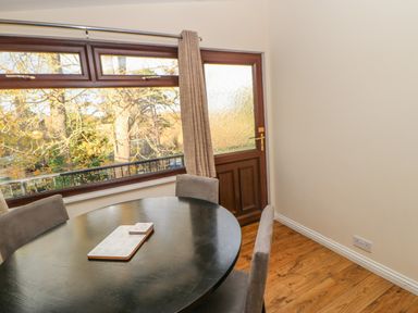 A dining area with a black round table and gray chairs next to a wooden door with a window at Bluebell Lodge in Saltburn-by-the-Sea