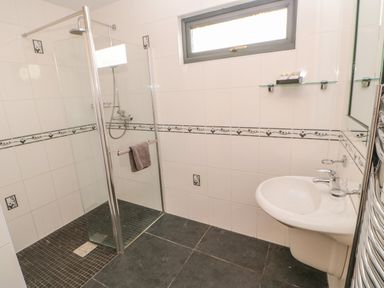 A bathroom with a walk-in shower and a sink with a mirror and glass shelf at Bluebell Lodge in Saltburn-by-the-Sea