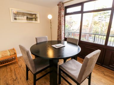 A dining room with a round black table and four chairs near a window at Violet Lodge in Saltburn-by-the-Sea