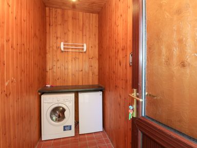 A small utility room with wooden panel walls a washing machine a mini fridge and a wooden counter at Violet Lodge in Saltburn-by-the-Sea