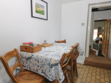 A dining area with a table covered with a patterned tablecloth and wooden chairs at Beck Cottage in Pickering