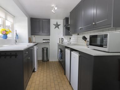 A kitchen with dark cabinets white countertops two small refrigerators and a microwave at Beck Cottage in Pickering