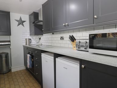 A kitchen with grey cabinets white tile backsplash two small fridges microwave toaster and kettle at Beck Cottage in Pickering