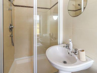 A bathroom with a shower enclosure and a sink with a mirror above at Brandon Holiday Home in Cloghane County Kerry