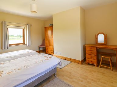 A bedroom with two single beds a wooden wardrobe a wooden dressing table with a mirror and a stool at Brandon Holiday Home in Cloghane County Kerry