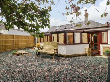 A garden with a wooden bench and gravel at Ty Taid in Llanddaniel Fab near Beaumaris