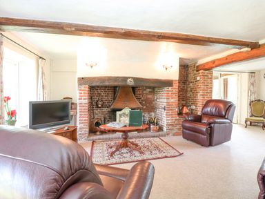 A living room with leather chairs a wooden coffee table and a brick fireplace at Lyons Green in Little Fransham near Swaffham