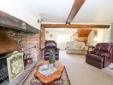 A living room with leather armchairs a floral sofa wooden coffee table and exposed wooden beams at Lyons Green in Little Fransham near Swaffham