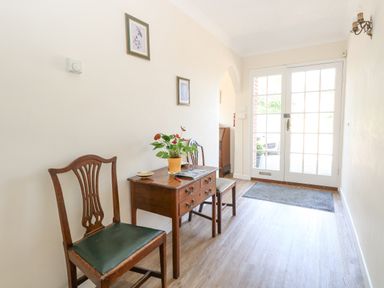 An entryway with two wooden chairs a wooden table with a plant and papers near glass double doors at Lyons Green Little Fransham near Swaffham
