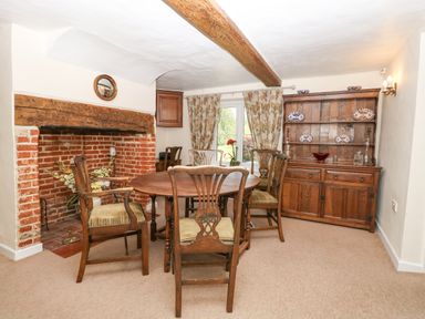 A dining room with a wooden table and chairs a brick fireplace and a wooden cabinet Lyons Green Little Fransham near Swaffham