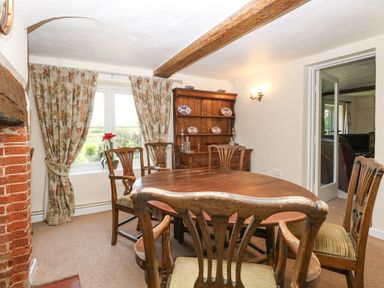A dining room with wooden table and chairs floral curtains and a wooden cabinet Lyons Green Little Fransham near Swaffham