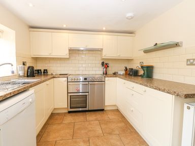 A kitchen with cream cabinets a stainless steel oven brown countertops and tiled floor at Lyons Green in Little Fransham near Swaffham