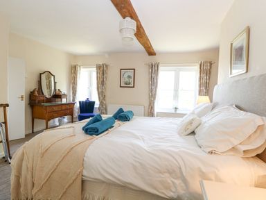 A bedroom with a bed towels on it a dressing table and chair at Lyons Green in Little Fransham near Swaffham