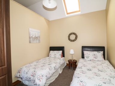 A bedroom with two single beds separated by a small wooden table with a lamp and a skylight at Rosemount Coach House Ballycarney near Enniscorthy County Wexford