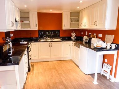 A kitchen with white cabinets black countertops and orange walls at Woodstone Barn Whitchurch near Tavistock