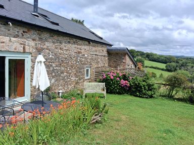 A garden with a bench and flowers at Woodstone Barn in Whitchurch near Tavistock