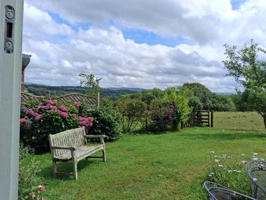 A garden with a bench and flowers at Woodstone Barn near Whitchurch near Tavistock