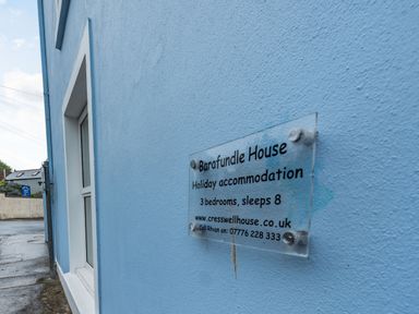 A blue exterior wall with a sign for Barafundle House holiday accommodation in Tenby