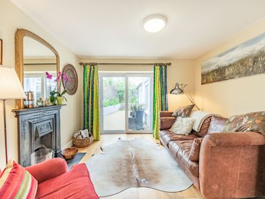 A living room with a brown leather sofa red armchair and a large mirror above a fireplace at Barafundle House in Tenby
