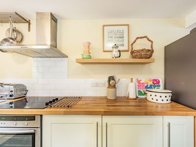 A kitchen countertop with oven stovetop toaster wicker basket and kitchen utensils at Barafundle House in Tenby