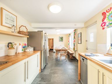 A kitchen with wooden countertops stainless steel appliances a dining table with chairs and colorful curtains at Barafundle House in Tenby