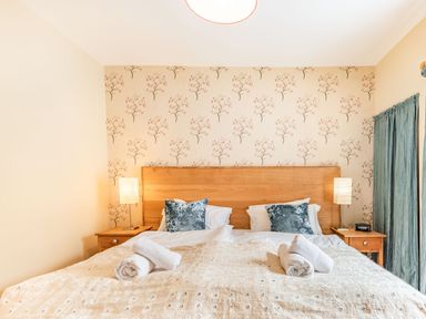A bedroom with a double bed wooden headboard bedside tables and lamps at Barafundle House in Tenby