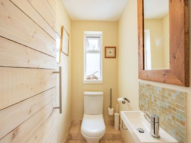 A small bathroom with a toilet sink mirror and window at Barafundle House in Tenby
