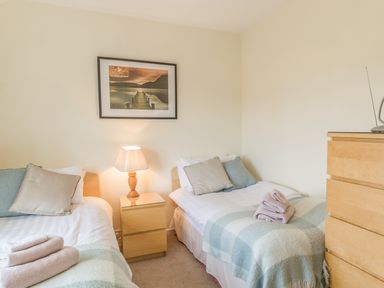A bedroom with two single beds bedside lamp a chest of drawers and a framed picture on the wall at Dune View in Beadnell