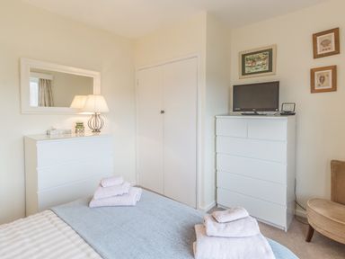 A bedroom with two white dressers a bed with towels a lamp and wall art at Dune View in Beadnell