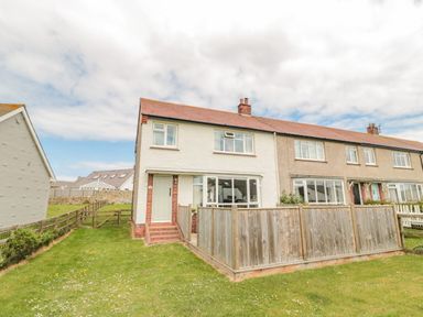 A row of houses with fenced front yards and grass at Dune View in Beadnell