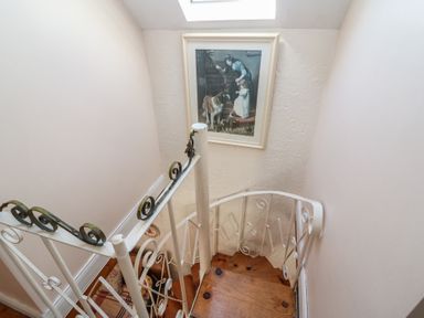 A staircase with a painting and wooden floor at Fuschia Cottage in Waterville, County Kerry