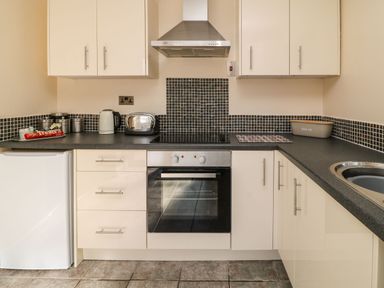 A kitchen with white cupboards a black countertop a toaster kettle oven and a tiled backsplash at 3 Rosecraddoc Lodge Rosecraddoc Lodge near Liskeard