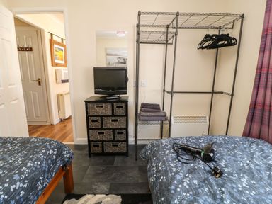 A bedroom with two beds a television on a chest of drawers an open closet with hangers and folded towels at 3 Rosecraddoc Lodge Rosecraddoc Lodge near Liskeard