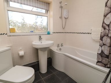 A bathroom with a toilet sink bathtub shower and a window with patterned glass at 3 Rosecraddoc Lodge Rosecraddoc Lodge near Liskeard