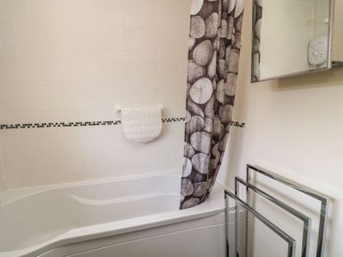 A bathroom with a bathtub and a shower curtain with stone pattern at 3 Rosecraddoc Lodge Rosecraddoc Lodge near Liskeard