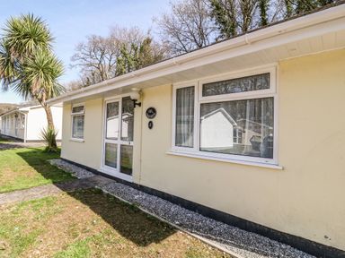 A yellow single-story building with white windows and door next to a palm tree at 3 Rosecraddoc Lodge Rosecraddoc Lodge near Liskeard
