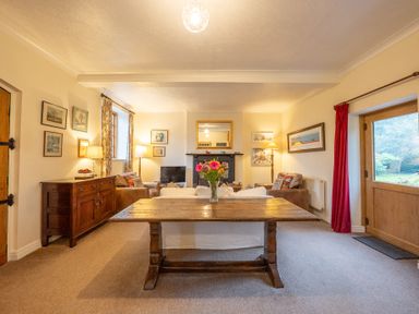 A living room with a wooden table and flowers in a vase at The Coach House in Gilwern near Crickhowell and Abergavenny