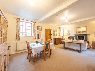 A combined dining and living room with wooden furniture and a fireplace at The Coach House in Gilwern near Crickhowell and Abergavenny