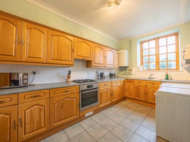 A kitchen with wooden cabinets a built-in oven a gas stove a microwave a kettle a toaster and a washing machine at The Coach House in Gilwern near Crickhowell and Abergavenny