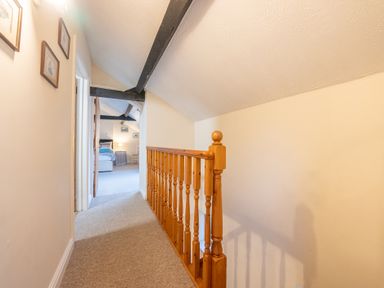 A hallway with carpet flooring and wooden railing leading to a bedroom at The Coach House in Gilwern near Crickhowell and Abergavenny