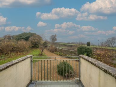 A balcony with metal railing overlooking a garden and fields with trees at The Coach House in Gilwern near Crickhowell and Abergavenny